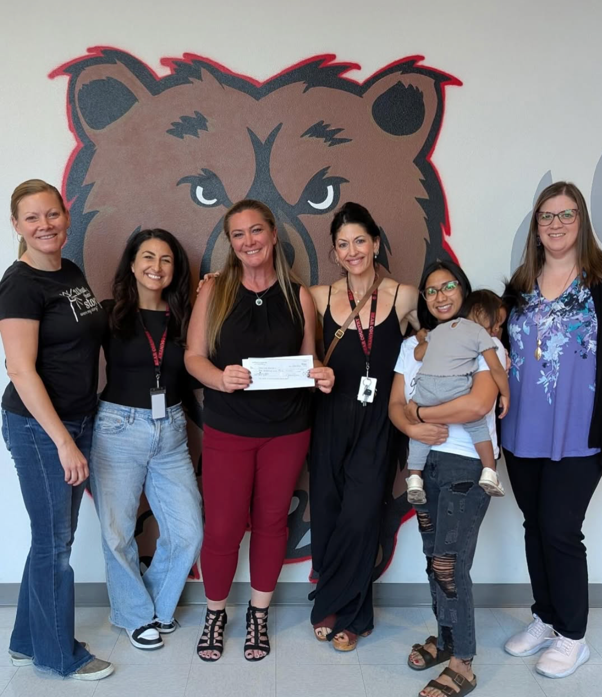 Aliante Bears PTO volunteers standing in front of the school bear mural